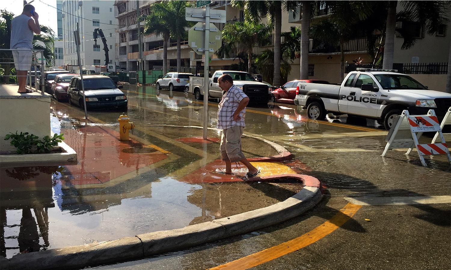 Hombre camina sobre acera inundada en Miami Beach